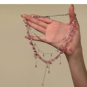 Detail einer mehrlagigen Silberkette mit rosa Kristallsteinen und Quastenanhängern