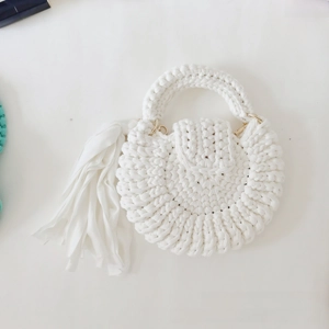 Detail of white handmade crochet round bag featuring spiral texture and golden hardware