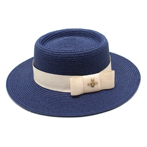 Close-up of navy straw boater hat with cream ribbon bow and golden bee detail