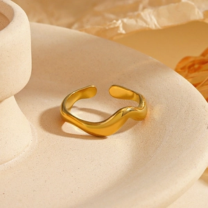 Détail d'une bague serpent dorée placée sur un plateau élégant en céramique