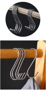 Detail of stainless steel S-hooks with protective balls hanging on a metal rod and wood
