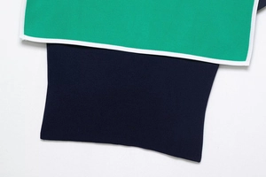 Detail of high-density knit fabric in green and navy with white piping edges