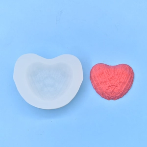 White heart-shaped silicone mold with detailed pink embossed candle craft on blue background