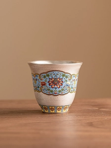 Macro detail of cloisonné enamel tea cup with intricate traditional patterns and silver rim