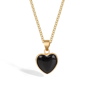 Detail view of a black heart crystal pendant with gold metal chain on a white background