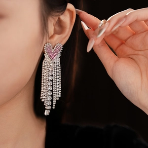Close-up of heart-shaped pink stud earring with shimmering diamond-set fringe detail