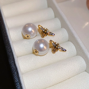 Elegant gold bee stud earrings with faux pearls and sparkling crystal accents in a jewelry box