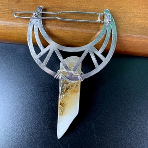 Close-up of silver moon hair clip with natural yellow crystal pendant on a black surface