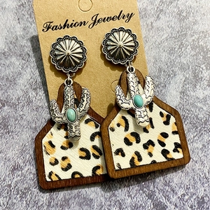 Detail of western boho earrings featuring turquoise stones, leopard print, and wood