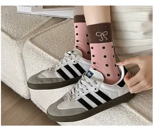 Detail of pink polka dot socks with bow embroidery styled with white Samba sneakers