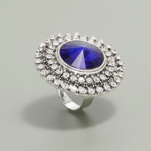 Close-up of a silver ring featuring a large round blue gemstone and crystal halo