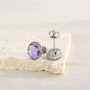 Macro view of purple gemstone earrings with silver prong setting on white stone