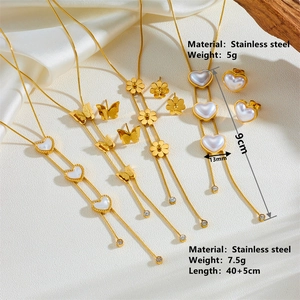 Golden stainless steel butterfly and heart necklace earring set on silk background