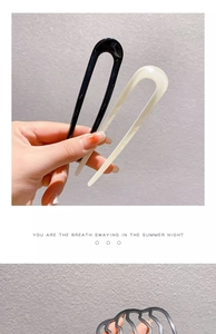 Detail of minimalist black and beige U-shaped hair pins with wavy hollow styling comb