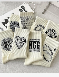 Detail of off-white cotton crew socks featuring black graphic prints and ribbed texture