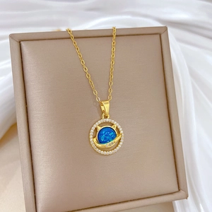Detailed shot of a gold cat-ear planet necklace with blue stone on a leather box