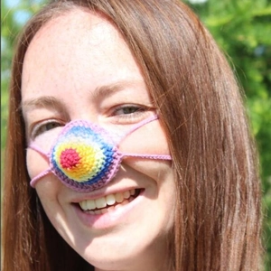 Close-up of a handmade rainbow knit nose warmer with colorful yarn and secure side straps