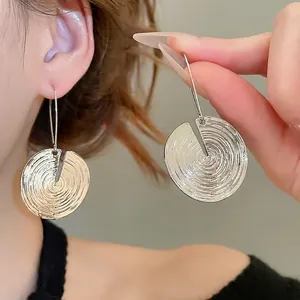 Elegant silver round earrings with concentric texture and radial notch on the earlobes