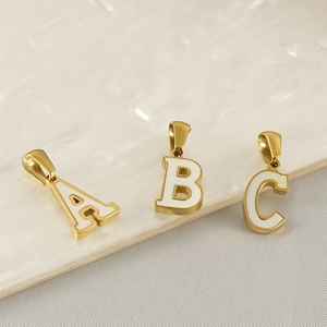 Macro detail of golden alphabet pendants A, B, and C with white enamel inlay accents