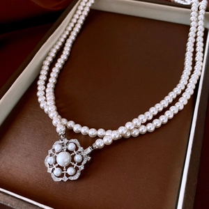 Close-up of double-layer pearl necklace with flower pendant in brown jewelry box
