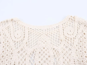 Close-up of crochet pattern and neckline detail on a beige long sleeve knit top