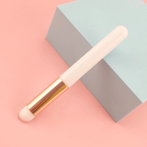 Detail of round head lip brush with gold ferrule and white bristles on pink background