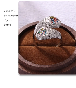 Macro detail of heart-shaped wing ring with colorful zircons on velvet jewelry box
