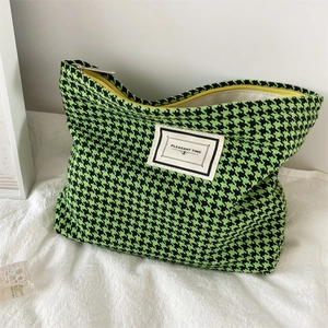 Detailed close-up of a houndstooth makeup bag featuring neon green patterns and a yellow zipper