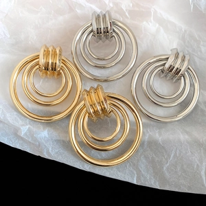 Makroaufnahme minimalistischer Gold- und Silber-Ohrringe mit dreilagigen konzentrischen Ringen