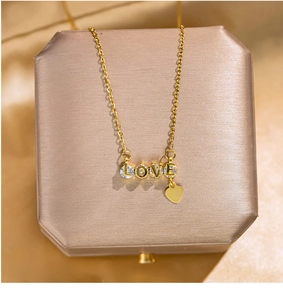 Macro shot of gold LOVE letter pendant with clear zircons and small heart tassel