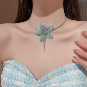 Close-up of a blue fabric flower pendant necklace with tassels on a model's neck