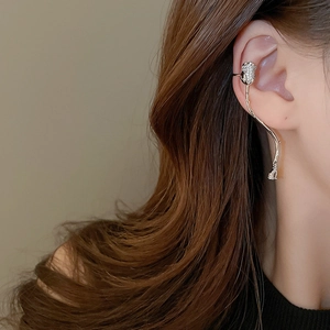 Detail of silver sparkling flower ear cuff with tassels shown on a model ear