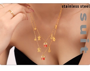Detail of Christmas themed stainless steel layered necklace set with festive charms on model