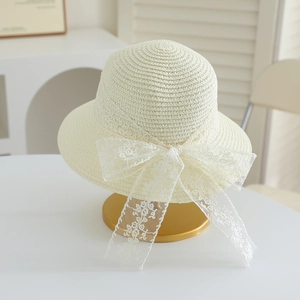 Detail of cream woven straw hat featuring an elegant large floral lace bow decoration