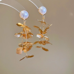 Detailed macro shot of golden leaf tassels and white pearl on elegant drop earrings