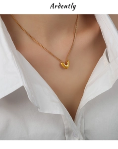 Gros plan d'un collier à pendentif en V plaqué or poli sur un cou avec une chemise blanche