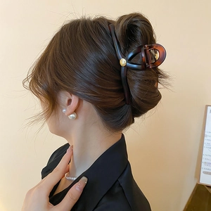 Détail d'une pince à cheveux en résine ambrée avec bouton métallique doré sur modèle