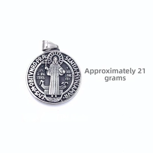 Macro view of vintage Saint Benedict medal pendant in stainless steel showing relief detail