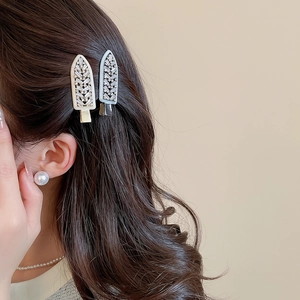 Detail view of ice cream shaped rhinestone hair clips and a pearl earring on a model