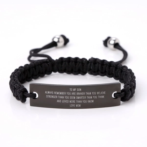 Macro detail of engraved inspirational message on black metal plate of woven bracelet