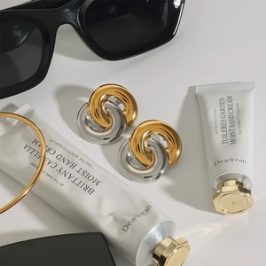 Interlocking gold and silver stainless steel hoop earrings in a minimalist fashion layout