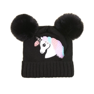 Détail de la broderie licorne et des pompons en fourrure sur un bonnet en tricot noir enfant