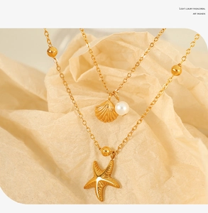 Macro view of gold double-layer necklace with starfish shell and white pearl pendants
