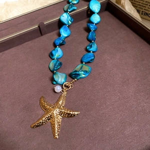 Detailed view of sea star pendant and blue shell beads necklace in an elegant gift box