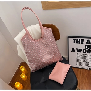Close-up of pink rhinestone checkered tote bag set on a black chair with white blazer