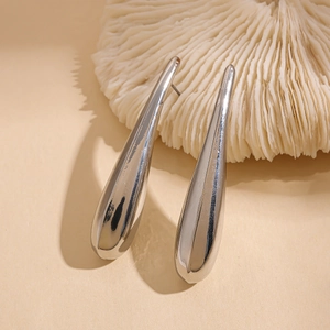 Macro detail of polished silver teardrop earrings with a mirrored metallic finish