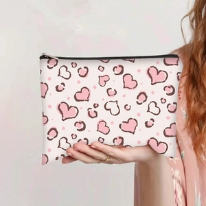 Detail of canvas makeup bag with pink heart and leopard prints being held by a hand