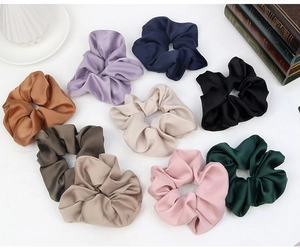 Detailed view of large satin scrunchies in multiple colors on a clean white background