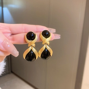 Detail view of vintage gold earrings with twisted texture and black teardrop stones
