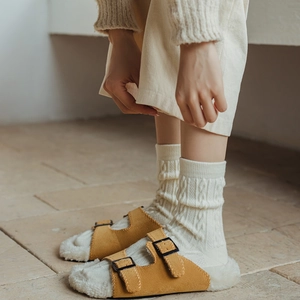 Détail de sandales en peluche jaune à boucles et chaussettes en tricot torsadé blanc